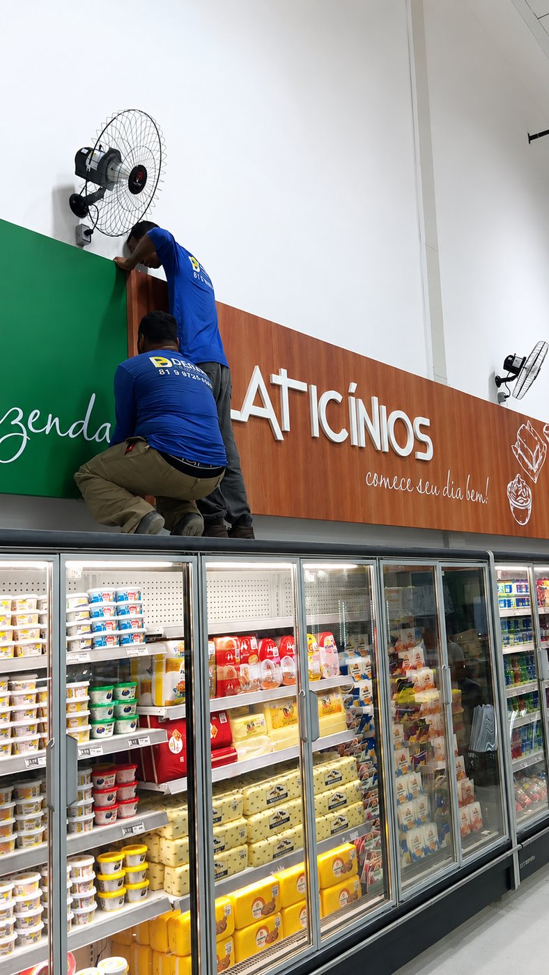 Equipe instalando letreiro de laticínios